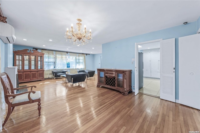 living room featuring a notable chandelier, an AC wall unit, and light hardwood / wood-style flooring