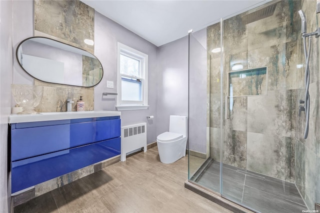 bathroom with radiator heating unit, hardwood / wood-style floors, an enclosed shower, toilet, and vanity