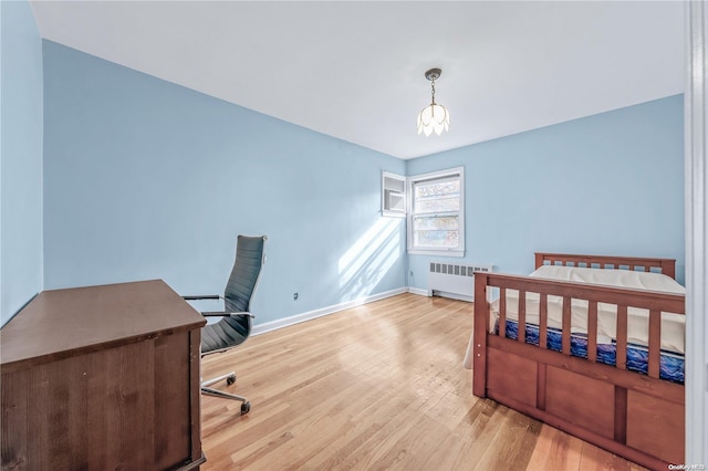 bedroom with radiator heating unit, a notable chandelier, and light wood-type flooring