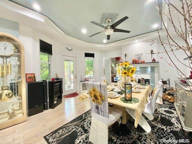 dining space featuring hardwood / wood-style floors, ceiling fan, ornamental molding, and a tray ceiling