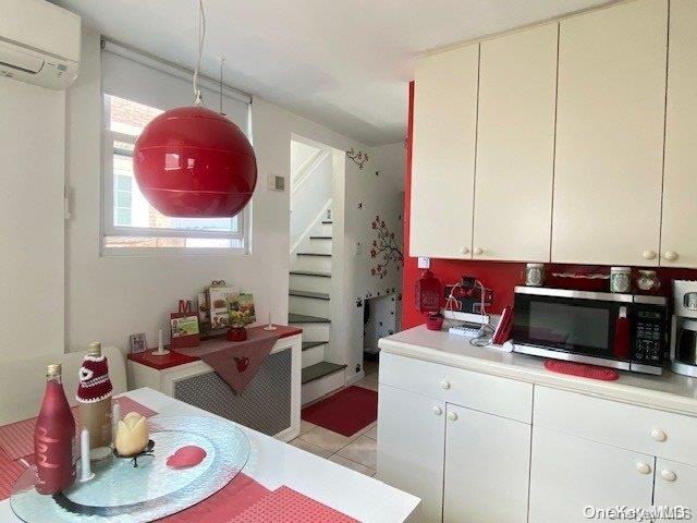 kitchen featuring a wall unit AC, white cabinets, and light tile patterned floors