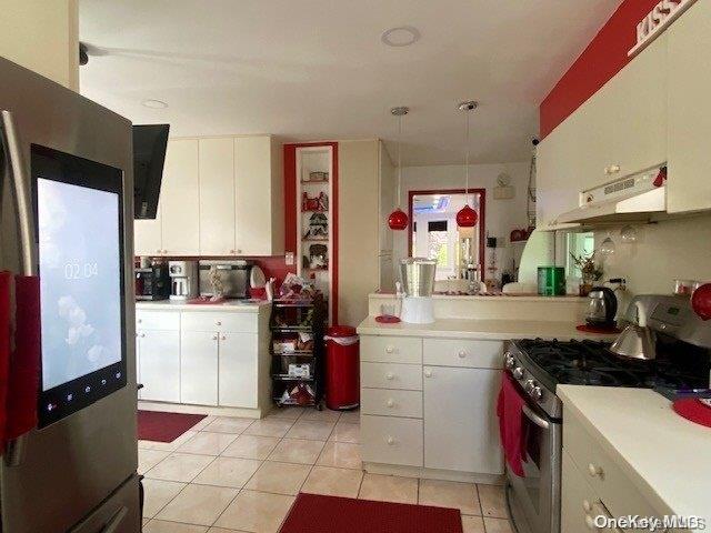 kitchen featuring white cabinets, light tile patterned floors, stainless steel appliances, and hanging light fixtures