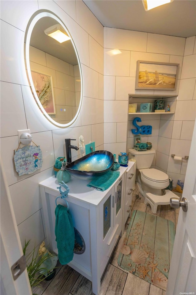 bathroom featuring hardwood / wood-style flooring, vanity, tile walls, and toilet