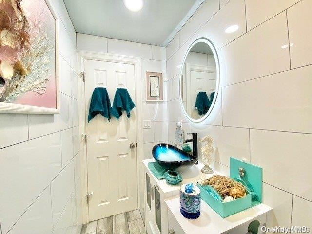 bathroom featuring vanity, hardwood / wood-style flooring, and tile walls