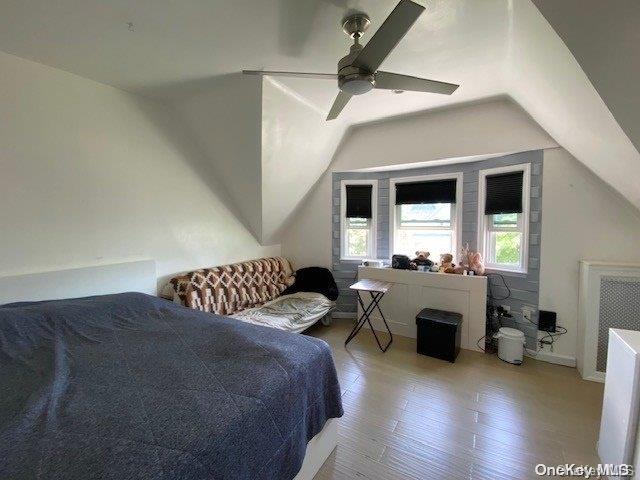 bedroom with ceiling fan, lofted ceiling, and light wood-type flooring