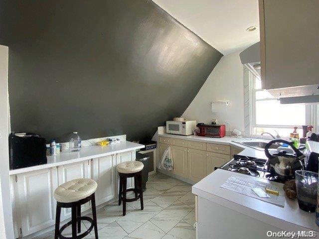 kitchen featuring a kitchen bar, kitchen peninsula, lofted ceiling, and sink