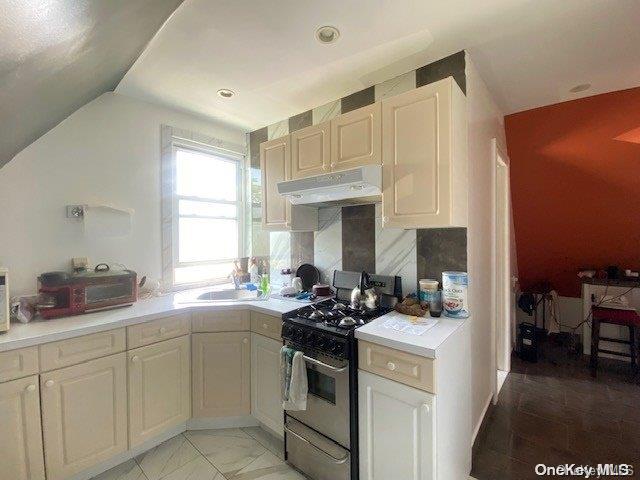 kitchen with tasteful backsplash, lofted ceiling, sink, and black / electric stove