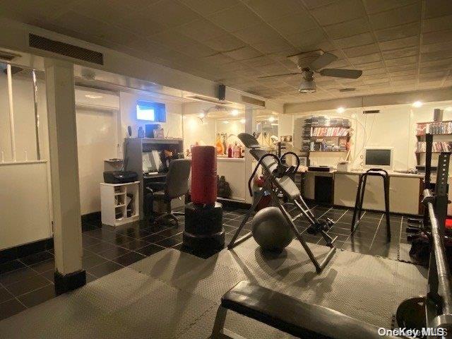 exercise room with dark tile patterned floors and ceiling fan