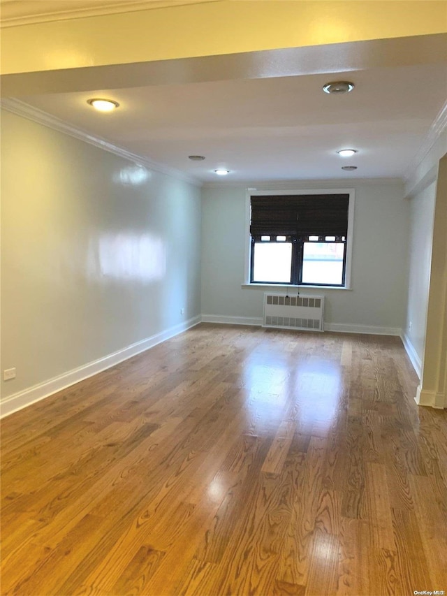 unfurnished room featuring wood-type flooring, radiator heating unit, and ornamental molding