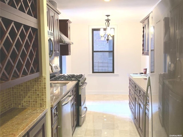 kitchen with pendant lighting, wall chimney exhaust hood, appliances with stainless steel finishes, dark brown cabinetry, and a chandelier