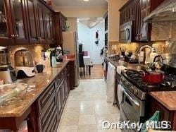 kitchen with decorative backsplash, light stone countertops, dark brown cabinets, and stainless steel appliances