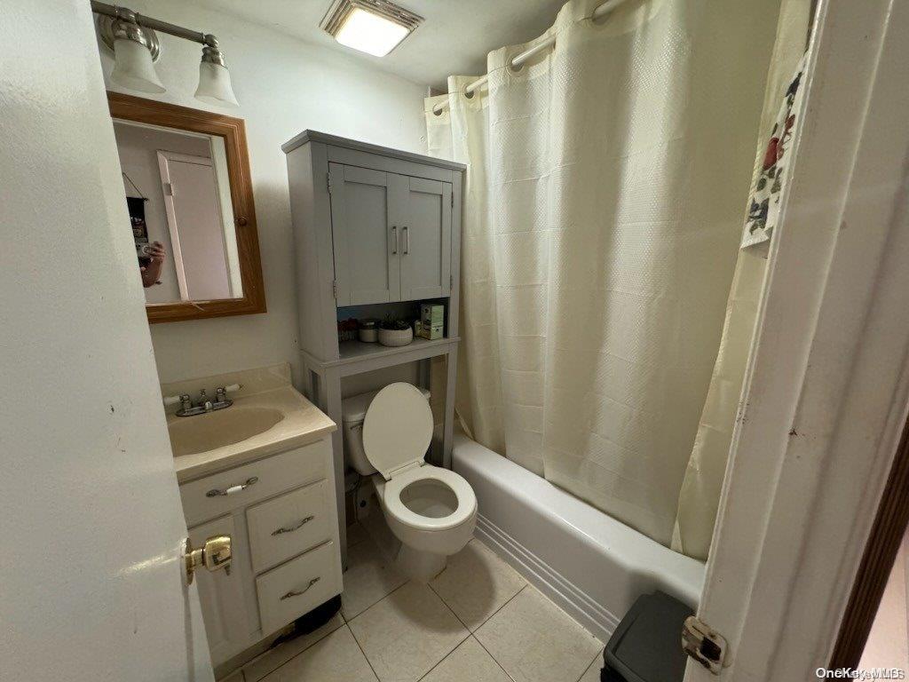 full bathroom featuring tile patterned flooring, vanity, shower / bath combination with curtain, and toilet