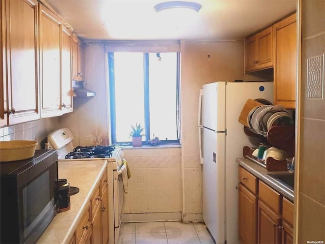 kitchen featuring sink, white appliances, and tile walls