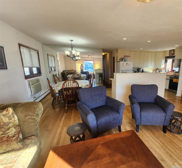 living room with a chandelier, baseboard heating, a wall mounted AC, and light hardwood / wood-style flooring