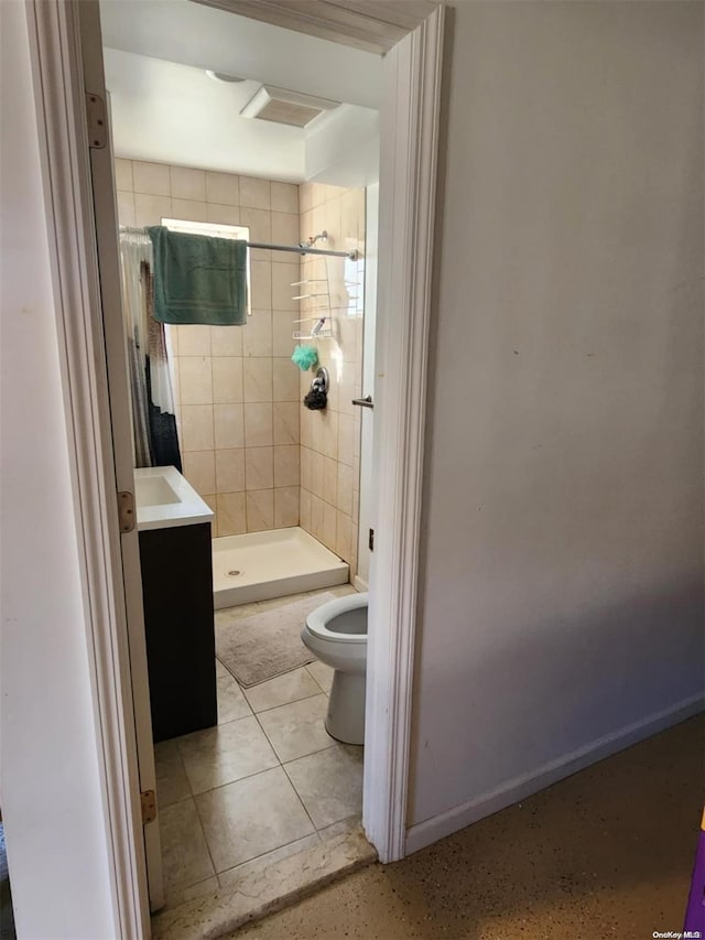 bathroom with tile patterned flooring, a tile shower, vanity, and toilet