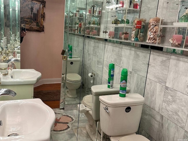 bathroom with toilet, sink, and tile walls