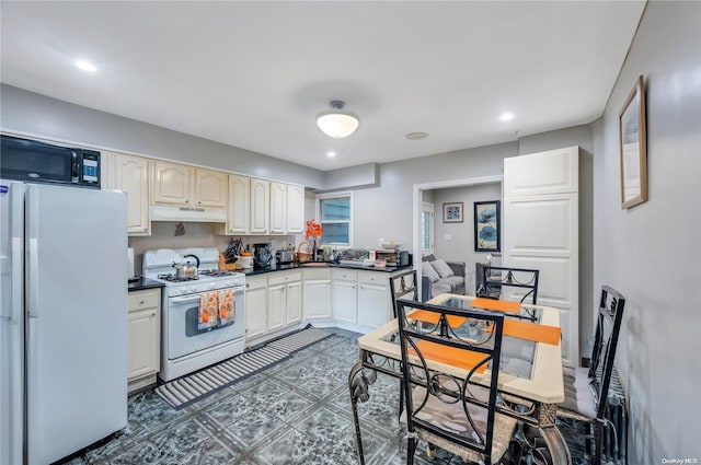 kitchen featuring white appliances and dark tile patterned floors