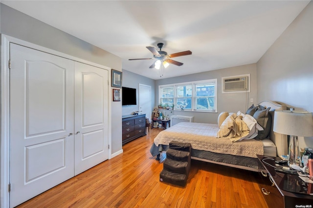 bedroom featuring ceiling fan, a closet, light hardwood / wood-style flooring, and a wall mounted AC