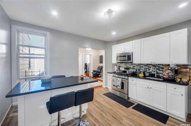 kitchen featuring a kitchen bar, white cabinetry, appliances with stainless steel finishes, and tasteful backsplash