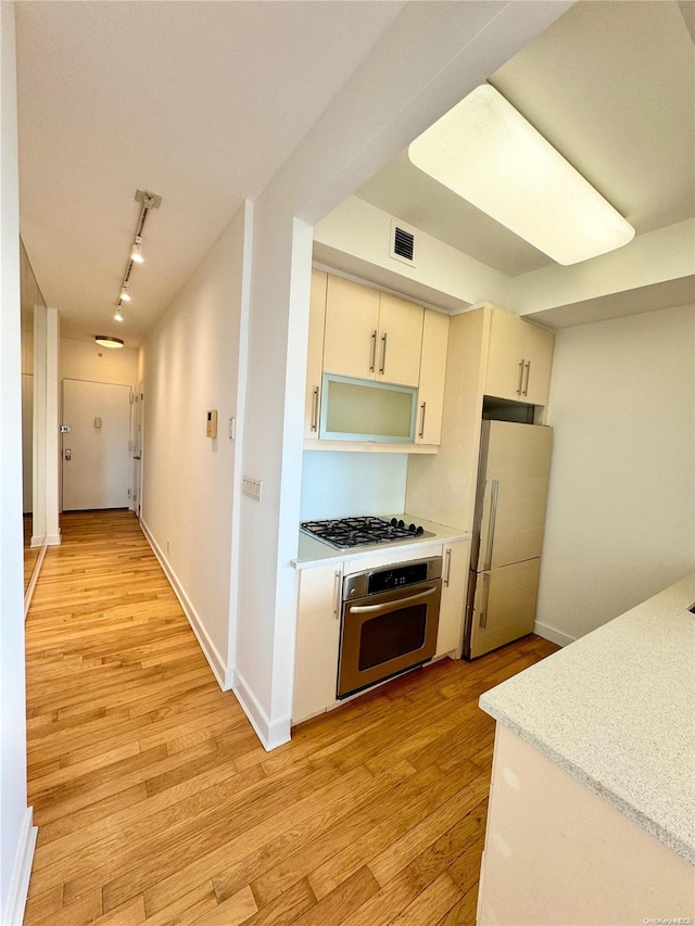 kitchen featuring white appliances, rail lighting, and light hardwood / wood-style flooring