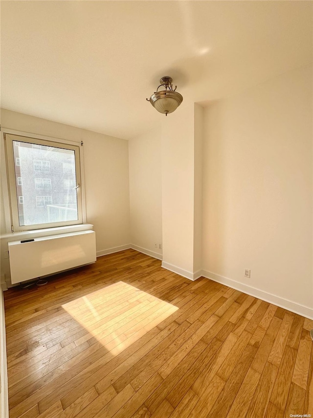 unfurnished room with radiator heating unit and light wood-type flooring