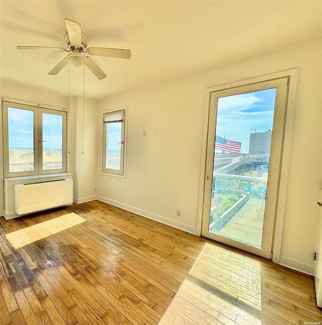 interior space featuring radiator heating unit, light wood-type flooring, and ceiling fan