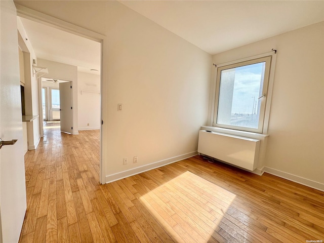 spare room featuring a wealth of natural light, radiator heating unit, and light wood-type flooring