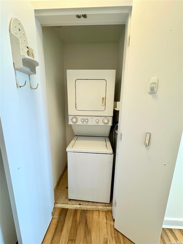 laundry room featuring light wood-type flooring and stacked washer / drying machine