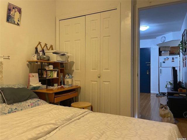 bedroom featuring white refrigerator, dark hardwood / wood-style floors, and a closet