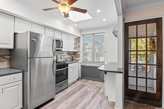 kitchen with white cabinets, decorative backsplash, stainless steel appliances, and radiator