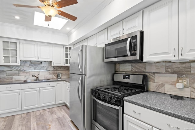 kitchen with ornamental molding, stainless steel appliances, sink, light hardwood / wood-style flooring, and white cabinets