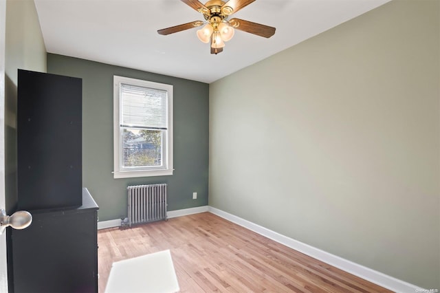 unfurnished room featuring radiator heating unit, light hardwood / wood-style flooring, and ceiling fan