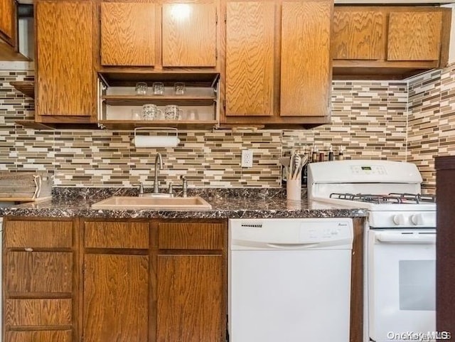 kitchen featuring decorative backsplash, white appliances, dark stone countertops, and sink