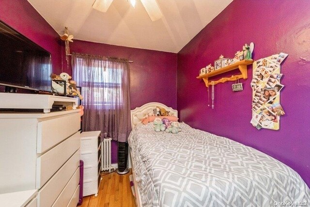 bedroom featuring ceiling fan, light wood-type flooring, and lofted ceiling