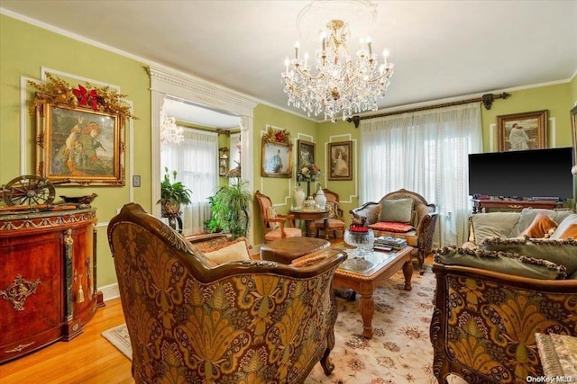 living area with a healthy amount of sunlight, light wood-type flooring, ornamental molding, and an inviting chandelier