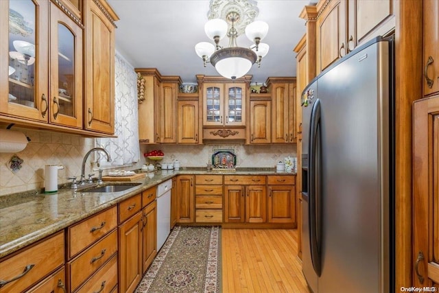 kitchen with light wood-type flooring, tasteful backsplash, sink, a chandelier, and stainless steel fridge with ice dispenser