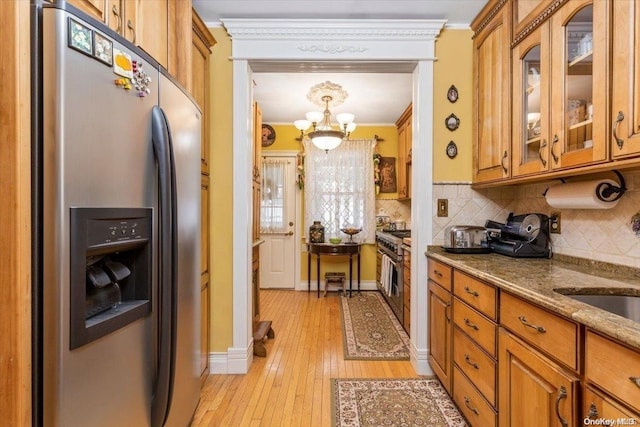 kitchen featuring crown molding, light hardwood / wood-style floors, light stone counters, stainless steel appliances, and a chandelier