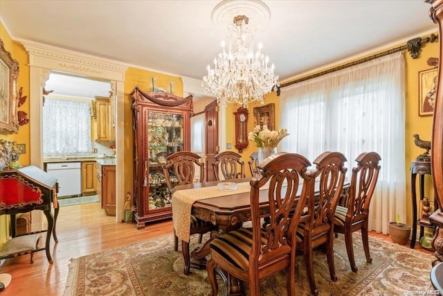 dining space with light hardwood / wood-style floors, crown molding, a wealth of natural light, and a chandelier