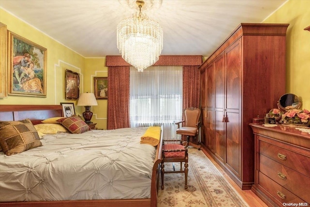 bedroom with a notable chandelier and light wood-type flooring