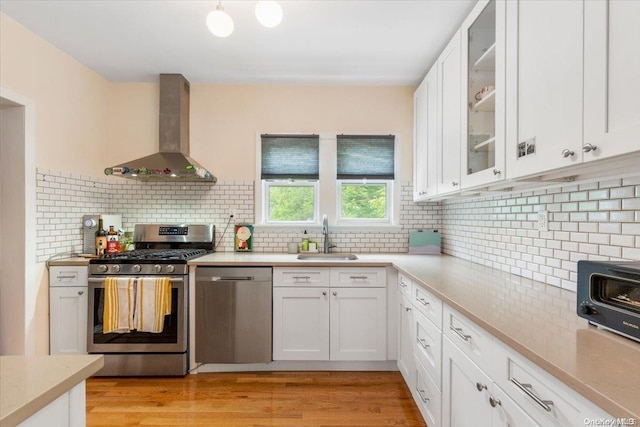 kitchen with white cabinets, wall chimney exhaust hood, and stainless steel appliances