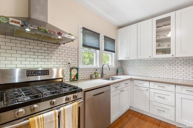 kitchen featuring white cabinetry, sink, stainless steel appliances, and wall chimney range hood