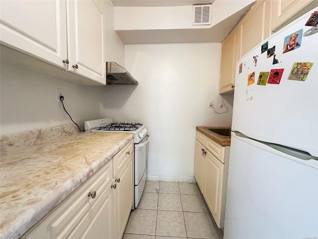 kitchen featuring range hood, light tile patterned floors, and white appliances