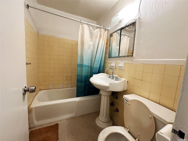 full bathroom with sink, tile patterned flooring, toilet, tile walls, and shower / tub combo