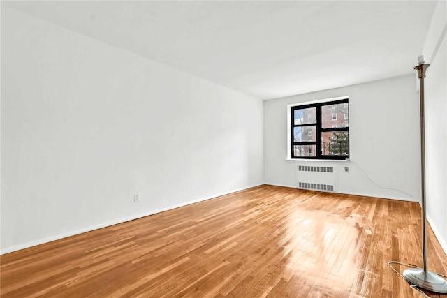 empty room with hardwood / wood-style floors and radiator heating unit