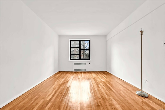 unfurnished room featuring hardwood / wood-style floors and radiator heating unit