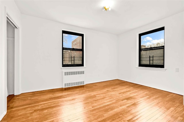 empty room with radiator heating unit and light wood-type flooring