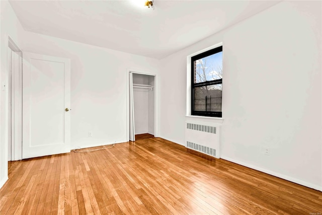 unfurnished bedroom with radiator, a closet, and light wood-type flooring