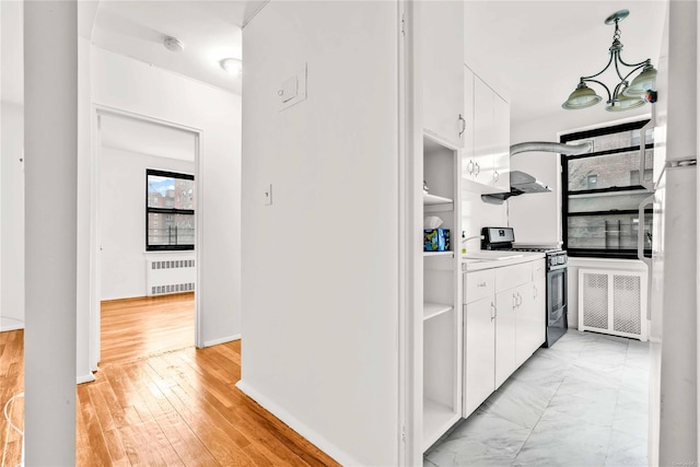 kitchen with white cabinetry, decorative light fixtures, stainless steel range with gas cooktop, radiator heating unit, and light hardwood / wood-style floors