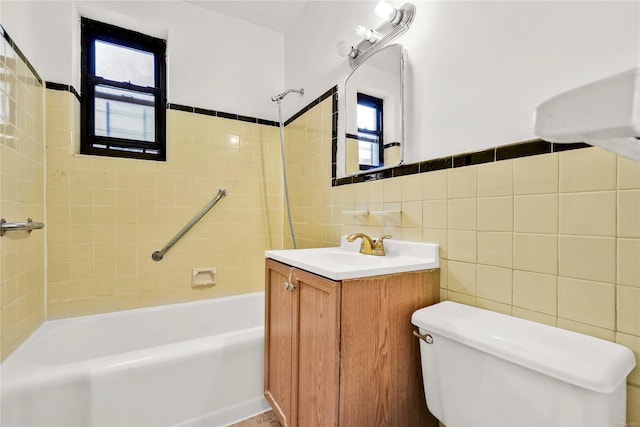 full bathroom with vanity, toilet, tiled shower / bath combo, and tile walls