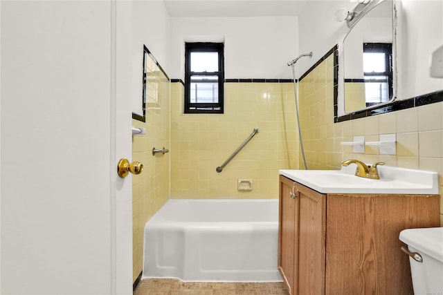 full bathroom featuring tiled shower / bath, vanity, toilet, and tile walls